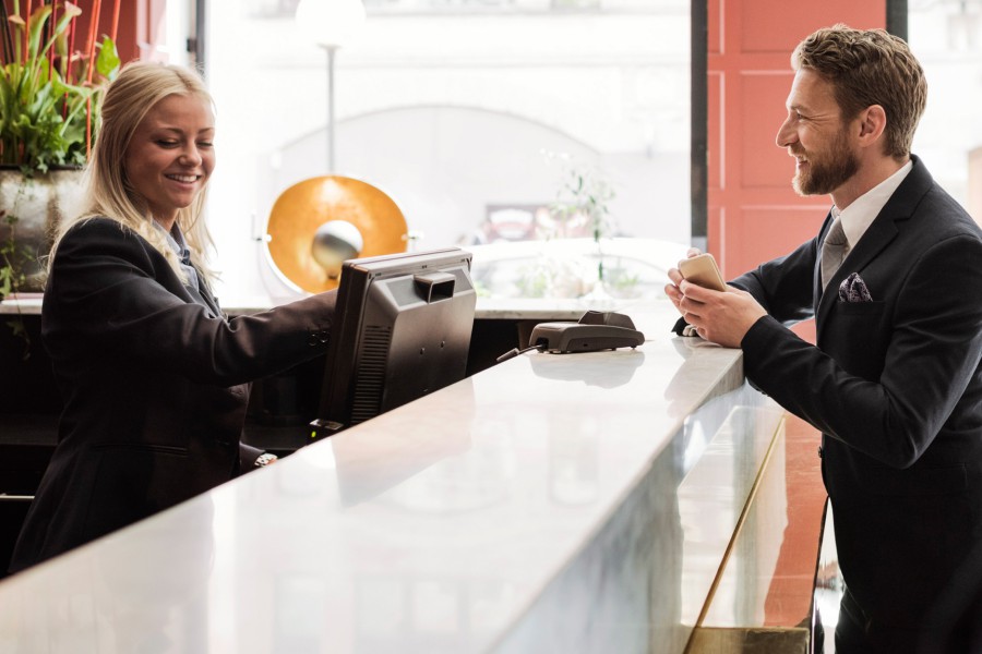 A young employee is welcoming a business traveller at a modern hotel reception.