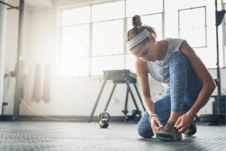 Eine Sportlerin bindet sich den Schuh.