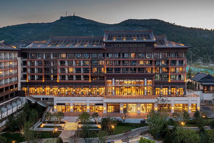 An impressive grand hotel in front of a mountain scenery at sundown.