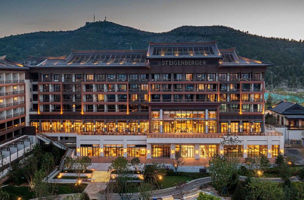 An impressive grand hotel in front of a mountain scenery at sundown.